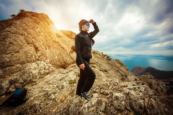 Woman tourist looks for way from the rocks top — Stock Photo, Image