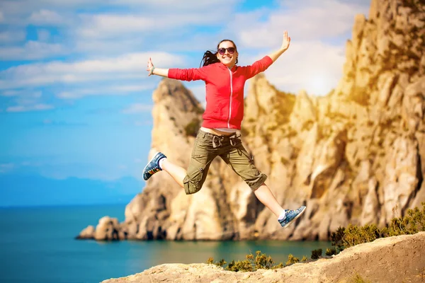 Young woman is jumping over mountain peak — Stock Photo, Image
