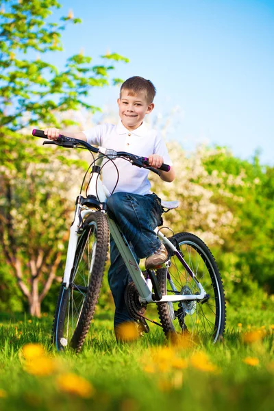 Kid in a green park on a bike — Stock Photo, Image