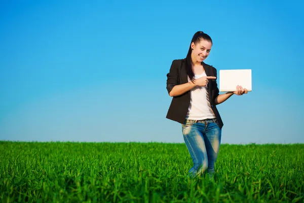 Zufriedene Geschäftsfrau auf der grünen Wiese mit einem Laptop. Sommer — Stockfoto
