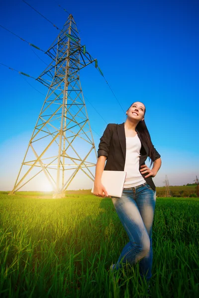 Cute woman in a green field with a laptop. power lines — Stock Photo, Image