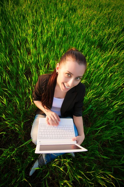 Fille heureuse dans un champ vert avec un ordinateur portable. été — Photo