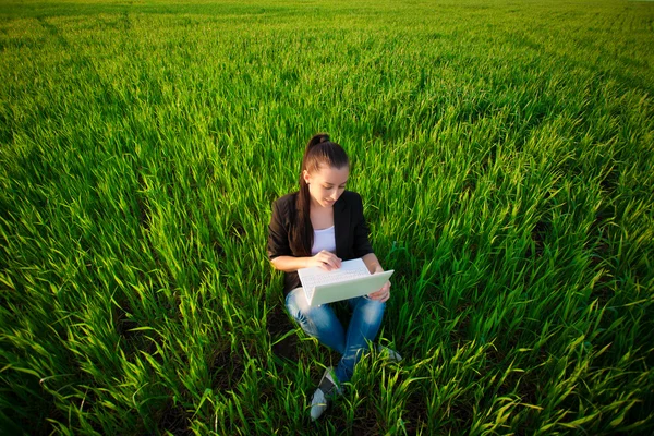 Happy girl in a green field with a laptop. summer — Stock Photo, Image