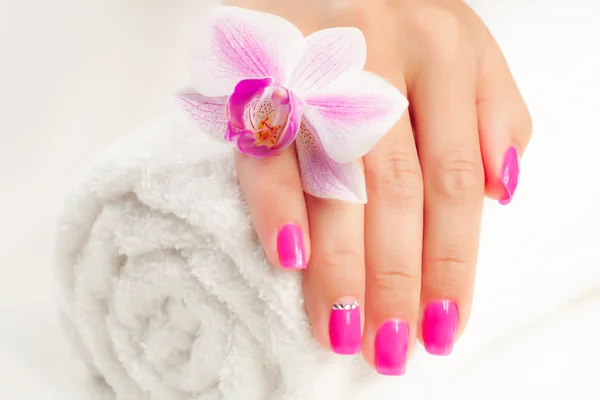 Hermosa manicura con orquídea rosa y toalla — Foto de Stock