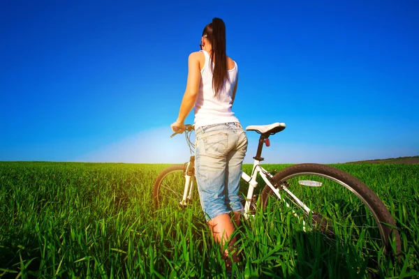 Kobieta w zielonym polu na rowerze. Wstecz — Zdjęcie stockowe