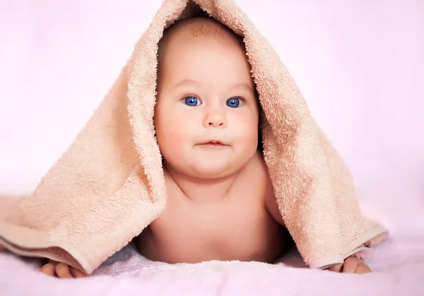Mutlu bebek bej terry havlunun altında saklanıyor — Stok fotoğraf