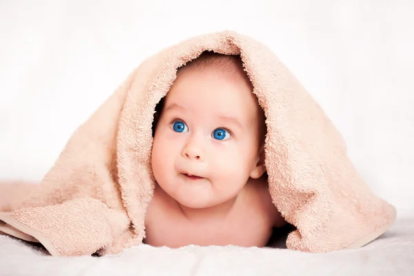 Bonito bebê menina está escondido sob o bege terry toalha — Fotografia de Stock