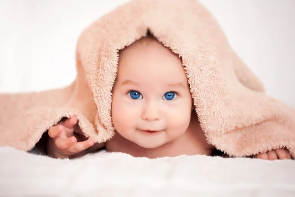 Baby versteckt sich unter dem beigen Frotteehandtuch — Stockfoto