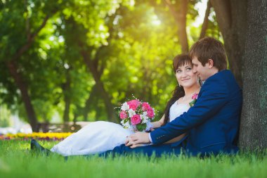 Gelin ve damat yeşil çimenlerin üzerinde oturuyorsun.