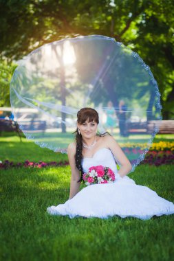 güzel bir gelin gelin peçe ile yeşil çimenlerin üzerinde oturuyor