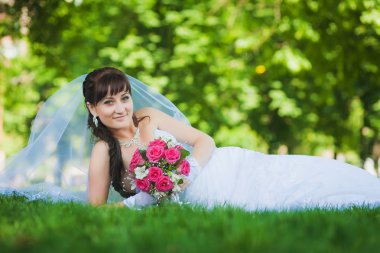 Gelin beyaz elbiseli yeşil çim üzerinde yalan