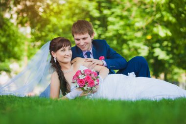 Gelin ve damat yeşil çim üzerinde yalan