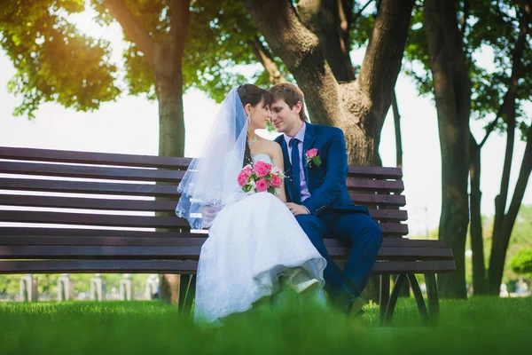 Nevěsta a ženich jsou sedí na lavičce — Stock fotografie