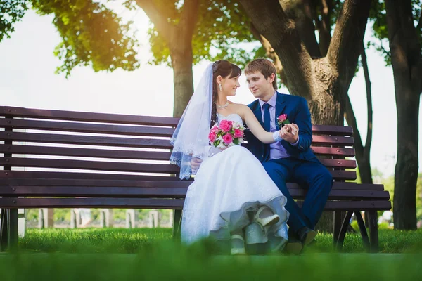 Happy bride and groom are sitting on the bench — Stock Photo, Image