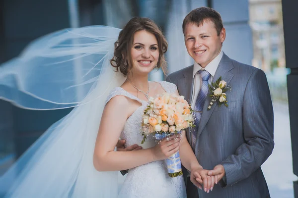 Bride and groom against a blue modern building — Stock Photo, Image