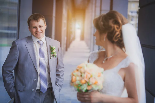 Bride and groom against a blue modern building — Stock Photo, Image