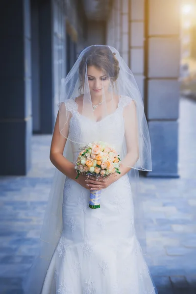 Felice sposa in abito bianco contro uno sfondo blu edificio moderno — Foto Stock