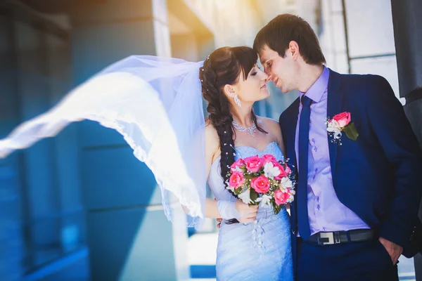 Happy newlyweds against a blue modern building background — Stock Photo, Image