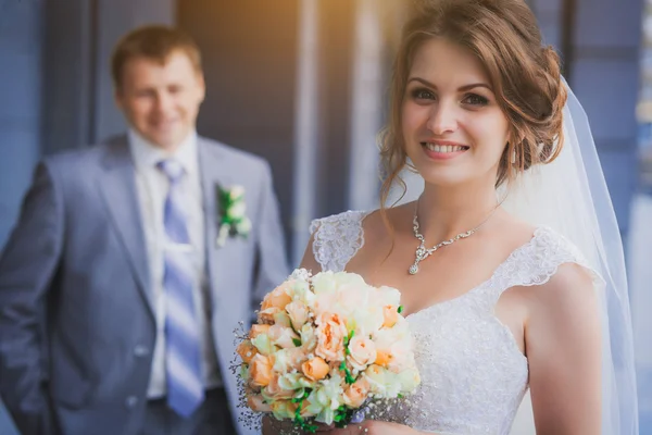 Bride and groom against a blue modern building — Stock Photo, Image