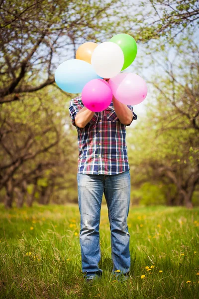 Hombre con globos en el prado verde de primavera —  Fotos de Stock