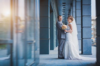 yeni evliler karşı mavi modern bir binada sarılıyorlar