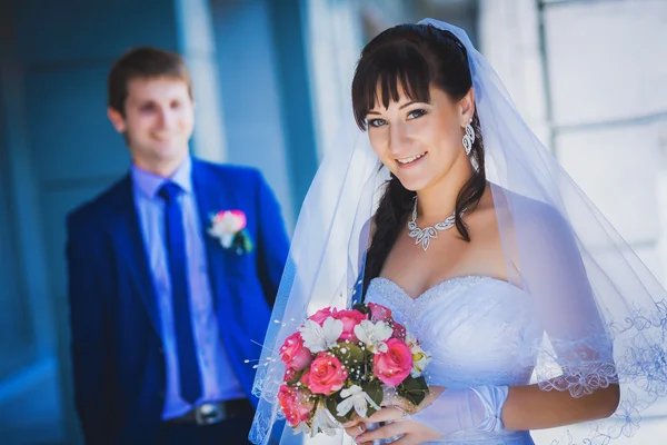 Felizes recém-casados contra um edifício moderno azul — Fotografia de Stock