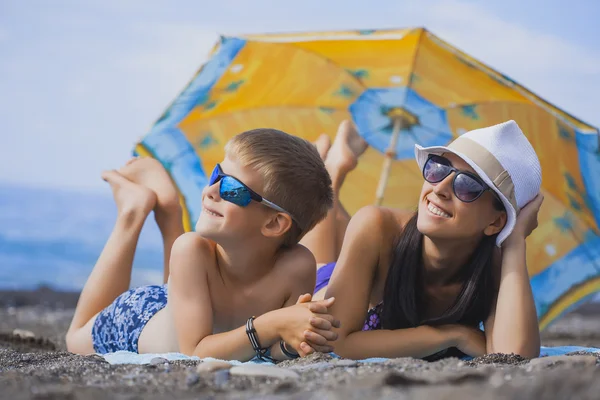 Felice sorridente mamma e figlio stanno prendendo il sole su una spiaggia — Foto Stock