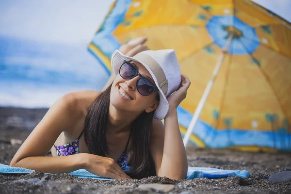 Menina sorridente feliz está tomando sol em uma praia — Fotografia de Stock