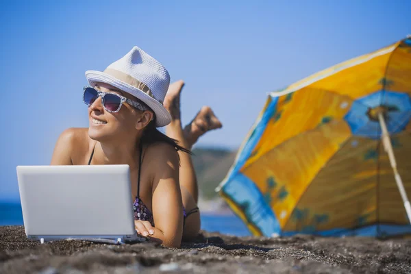 Menina sorridente feliz está tomando banho de sol com laptop — Fotografia de Stock