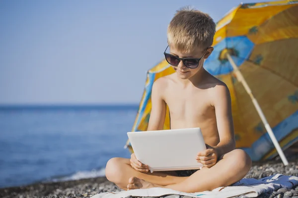 Glada leende barn med laptop på en strand — Stockfoto