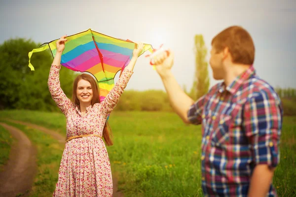 Loving couple are fling a kite on a spring meadow — Stock Photo, Image