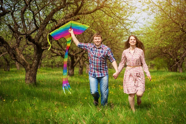 Happy couple are fling kite on a spring meadow — Stock Photo, Image