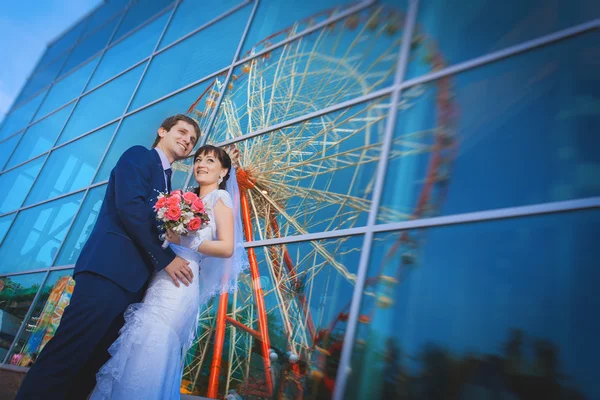 Feliz recém-casados perto do edifício de vidro azul — Fotografia de Stock