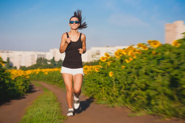 Athlete on morning jog in the sunflower\'s field