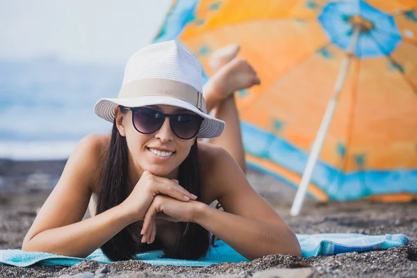 Felice sorridente ragazza sta prendendo il sole su una spiaggia — Foto Stock