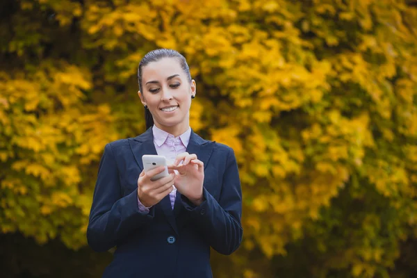 Businesswoman, on the autumn trees background — Stock Photo, Image