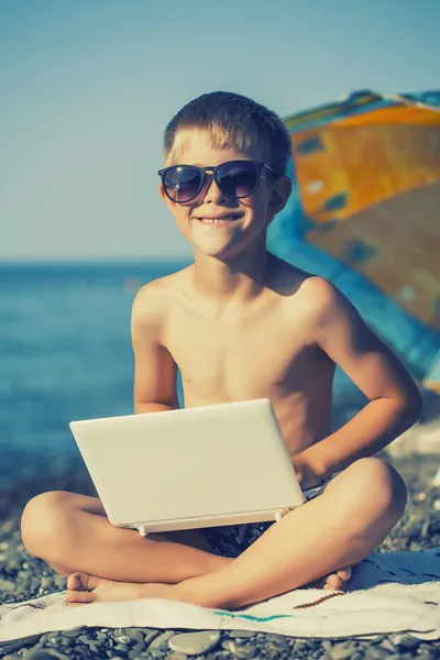 Happy smiling kid with laptop on a beach — Stock Photo, Image