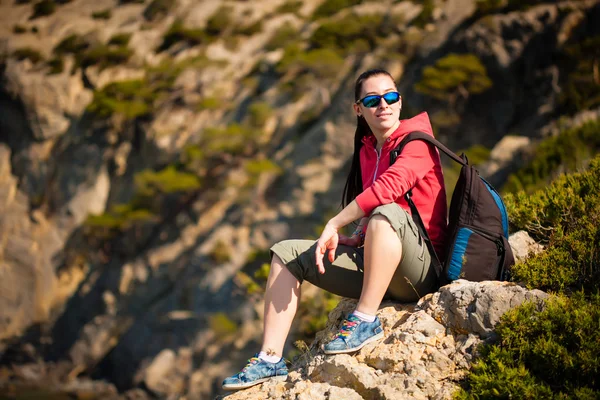 Unavený turista odpočívá na vrcholu hory se — Stock fotografie