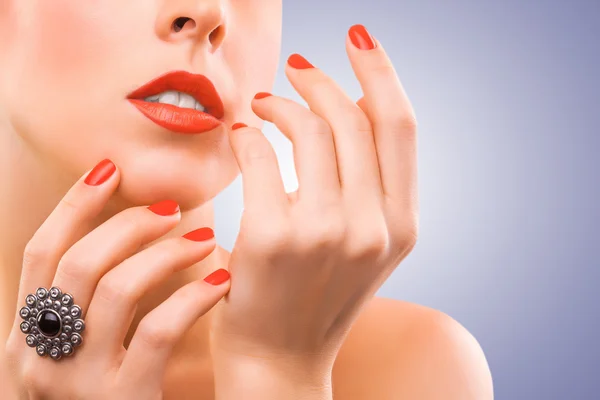 Gezicht en mooie rode manicure op de blauwe — Stockfoto