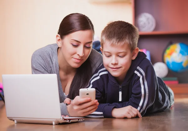 Mom and son are lying on wood flooring with laptop — Stock Photo, Image