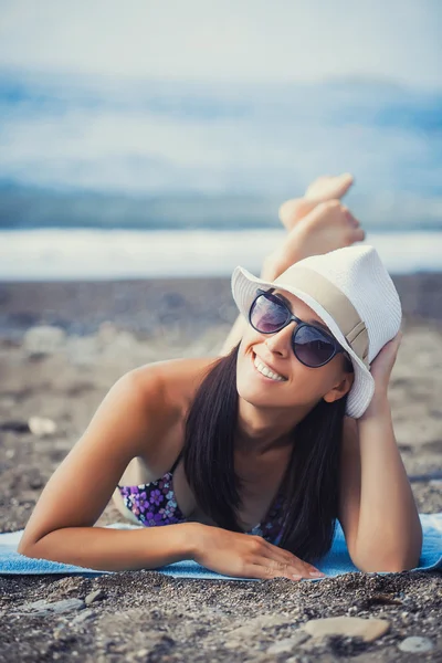 Menina bonita está tomando sol na praia — Fotografia de Stock