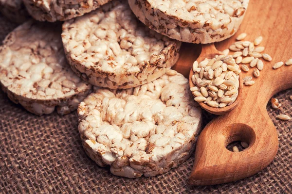 Pan crujiente, galletas de cereales y cuchara de madera con grano — Foto de Stock