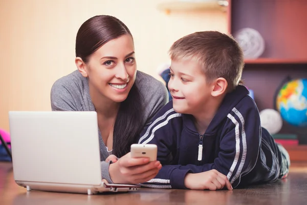 Mom and son are lying on wood floor with laptop — Stockfoto