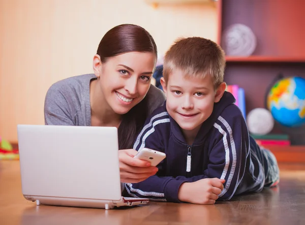 Mom and son are lying on wood floor with laptop — Stockfoto