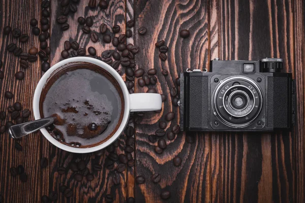 Xícara de café e câmera retro no fundo de madeira — Fotografia de Stock