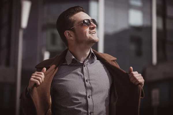 Hombre de moda frente a un edificio de vidrio con abrigo — Foto de Stock