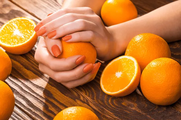 Beautiful orange manicure with oranges. on the wood — Stock Photo, Image