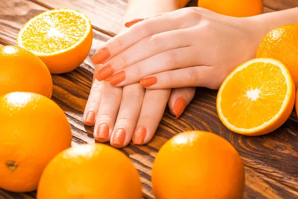 Beautiful orange manicure with oranges. on the wood — Stock Photo, Image