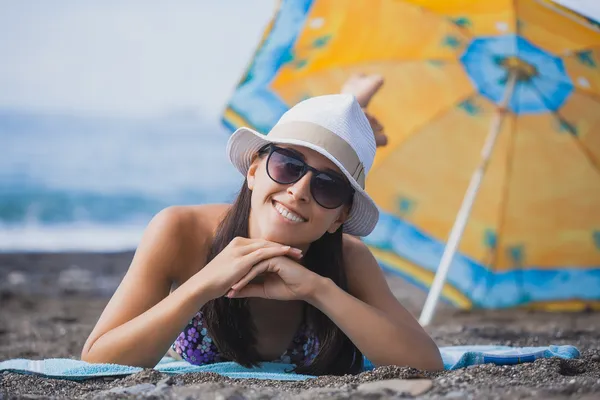 Flickan ligga på stranden med hatt och baddräkt — Stockfoto