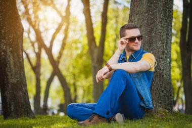 adam parkta yeşil çimenlerin üzerinde oturuyor